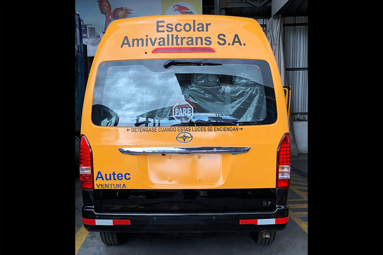 Parte posterior de una buseta amarilla con sticker escolar