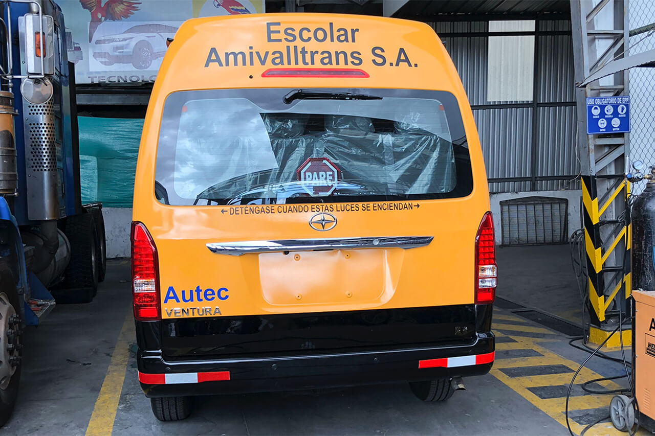 Parte posterior de una buseta amarilla con sticker escolar